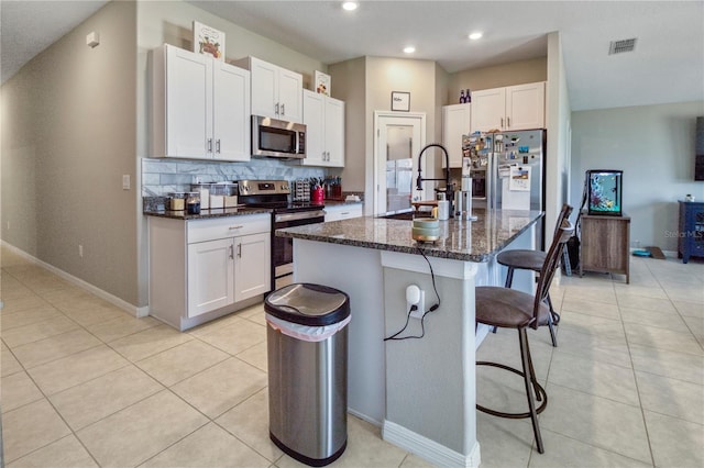 kitchen with white cabinetry, sink, a kitchen island with sink, a breakfast bar, and appliances with stainless steel finishes