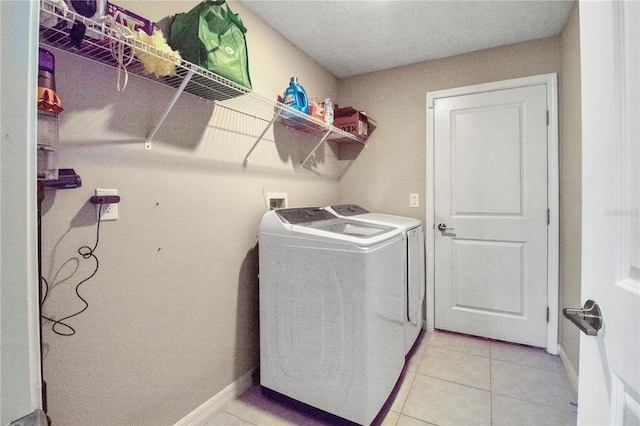 clothes washing area with light tile patterned flooring and washing machine and clothes dryer