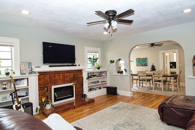 living room featuring ceiling fan, light hardwood / wood-style floors, and a textured ceiling