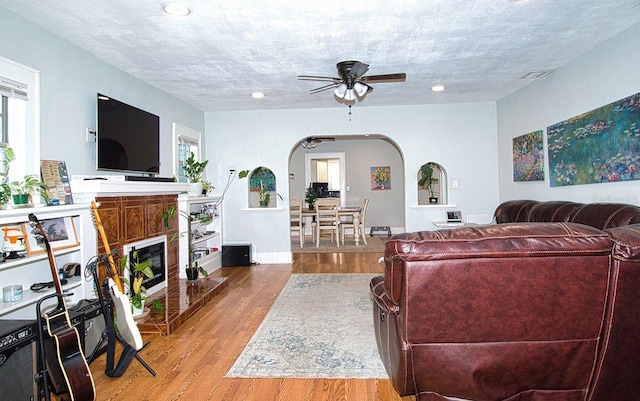 living room with a textured ceiling, hardwood / wood-style flooring, and ceiling fan