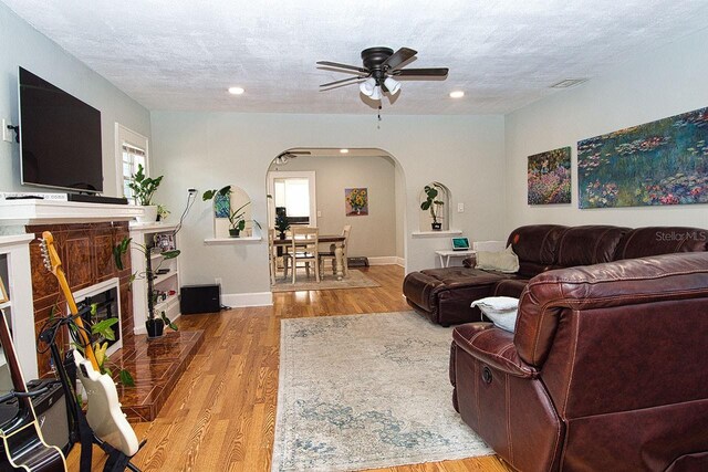 living room featuring a textured ceiling, light hardwood / wood-style floors, and ceiling fan