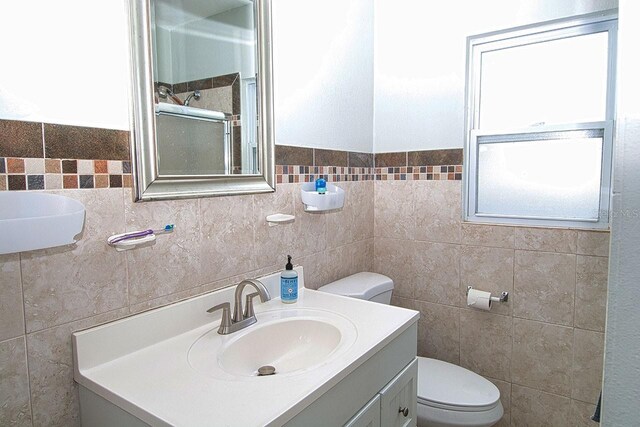 bathroom with vanity, tile walls, and toilet