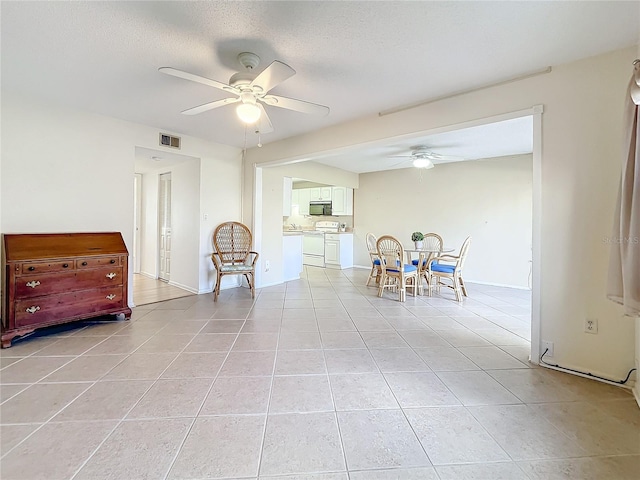 dining space featuring ceiling fan, light tile patterned floors, and a textured ceiling