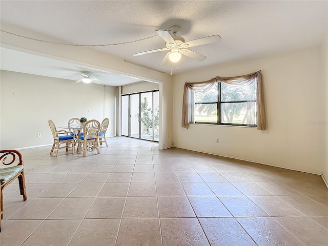 interior space with ceiling fan, light tile patterned floors, and a textured ceiling