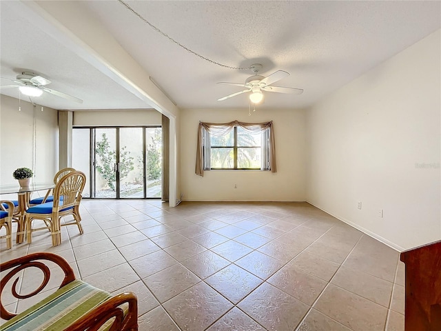 interior space with ceiling fan, light tile patterned floors, and a textured ceiling