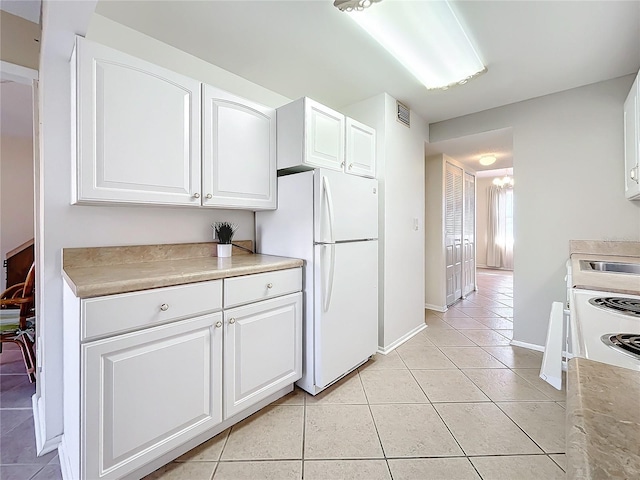 kitchen featuring white refrigerator, white cabinetry, light tile patterned floors, and an inviting chandelier