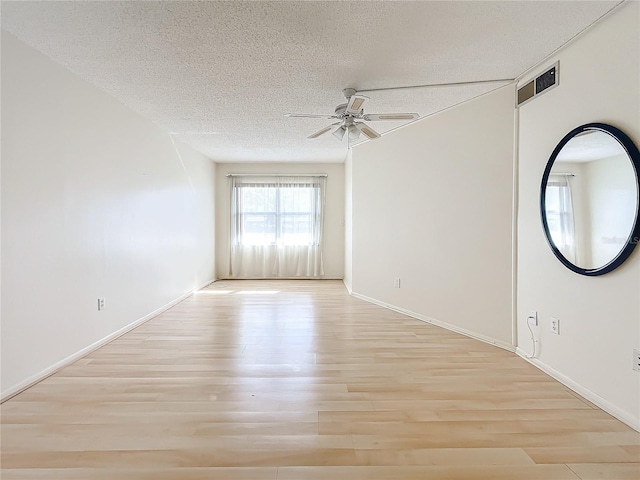 empty room featuring ceiling fan, light wood-type flooring, and a textured ceiling