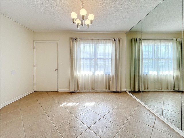 tiled empty room with a notable chandelier and a textured ceiling