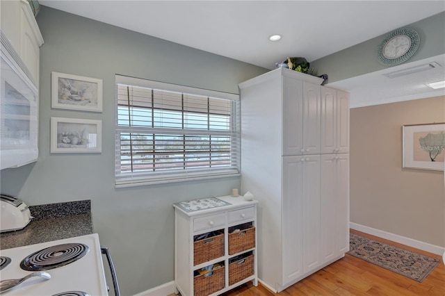 interior space with white range, light hardwood / wood-style floors, and white cabinetry