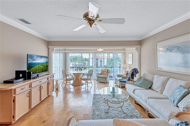 living room featuring crown molding, light hardwood / wood-style flooring, ceiling fan, and a textured ceiling