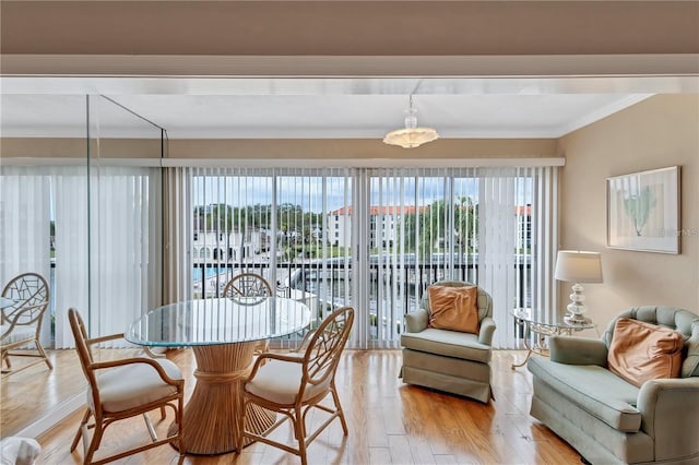 dining room with ornamental molding and light hardwood / wood-style flooring