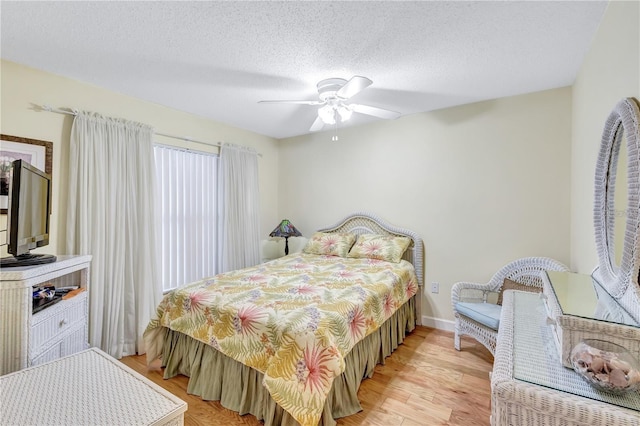 bedroom with a textured ceiling, light wood-type flooring, and ceiling fan