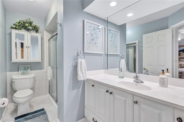 bathroom with walk in shower, tile patterned flooring, toilet, vanity, and tile walls