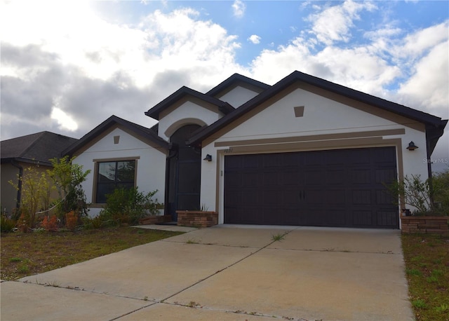 view of front of home featuring a garage, concrete driveway, and stucco siding