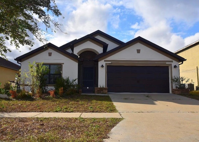 view of front facade featuring a garage, concrete driveway, central air condition unit, and stucco siding