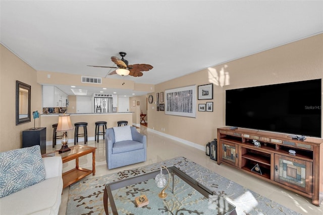 living room featuring ceiling fan, light tile patterned flooring, visible vents, and baseboards