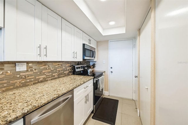 kitchen featuring decorative backsplash, white cabinetry, light stone counters, and appliances with stainless steel finishes