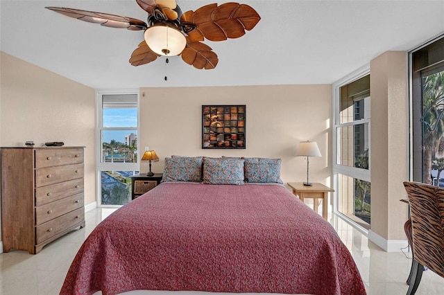 tiled bedroom with ceiling fan and a wall of windows