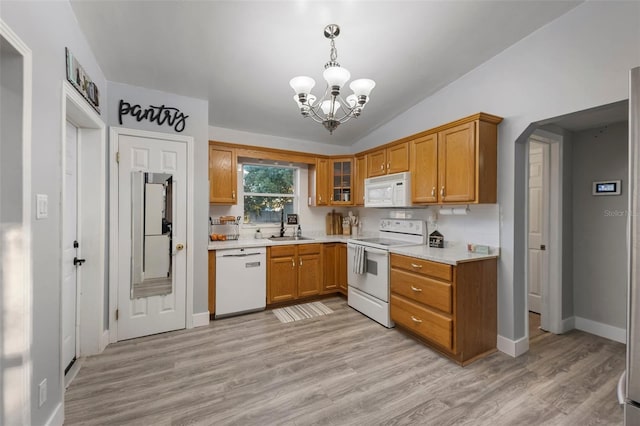 kitchen featuring vaulted ceiling, decorative light fixtures, white appliances, and light wood-type flooring