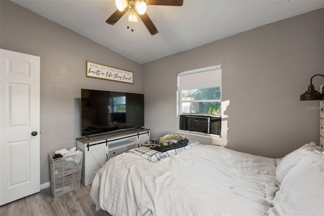 bedroom with ceiling fan, hardwood / wood-style floors, cooling unit, and vaulted ceiling