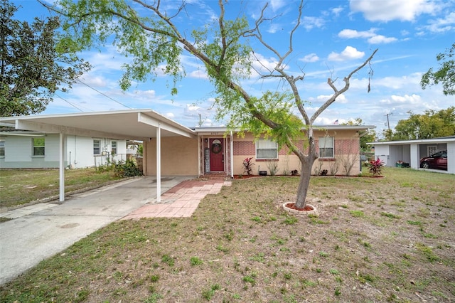 ranch-style home featuring an attached carport, concrete driveway, brick siding, and a front yard