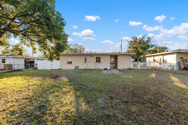 rear view of house with a yard and a fenced backyard