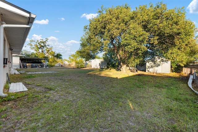 view of yard featuring fence, a storage unit, and an outbuilding