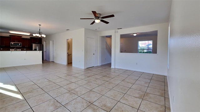 tiled spare room featuring ceiling fan with notable chandelier