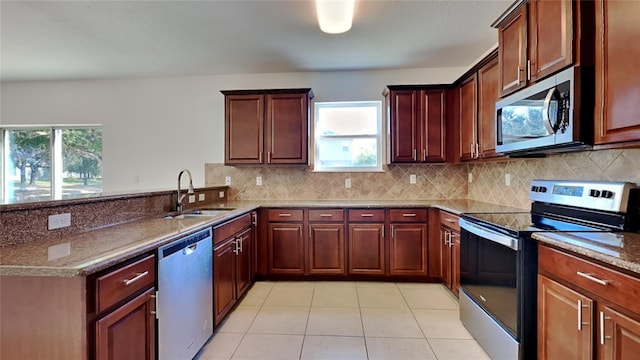 kitchen with appliances with stainless steel finishes, light tile patterned floors, a wealth of natural light, and sink