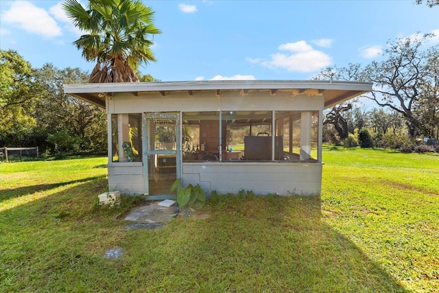 view of outbuilding featuring a sunroom and a yard