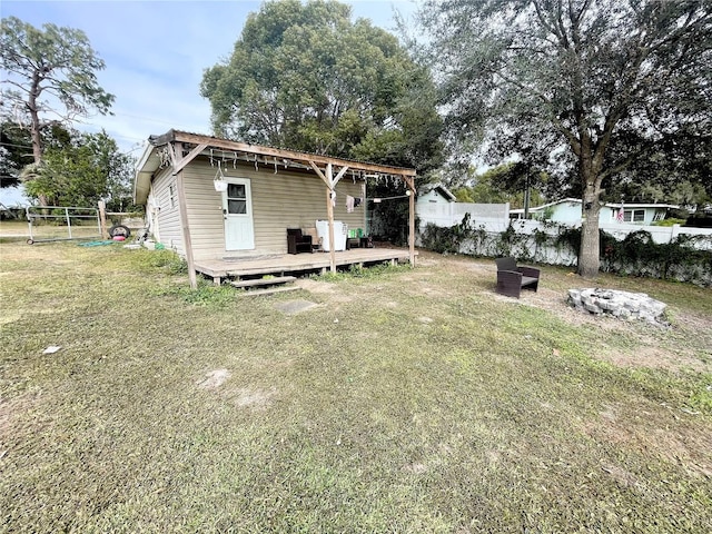 rear view of house featuring a deck, an outdoor fire pit, and a yard