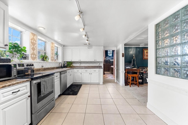 kitchen with tasteful backsplash, light colored carpet, sink, appliances with stainless steel finishes, and white cabinets