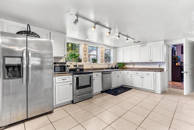 kitchen with light tile patterned floors, stainless steel appliances, decorative backsplash, and white cabinetry