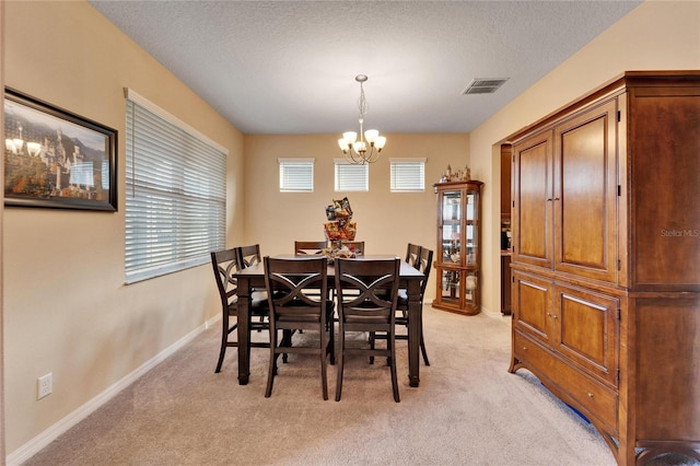 dining space featuring light colored carpet, a chandelier, and a textured ceiling