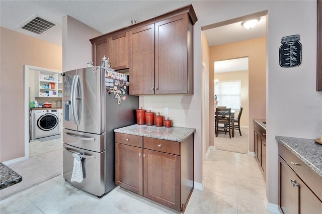 kitchen featuring light stone countertops, stainless steel fridge with ice dispenser, a textured ceiling, washer / dryer, and light carpet