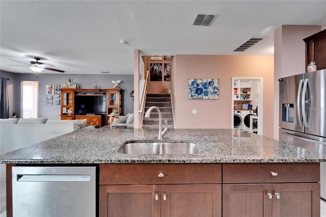 kitchen featuring a textured ceiling, stainless steel appliances, washer and clothes dryer, and sink