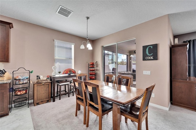 dining space with a textured ceiling, light colored carpet, and a notable chandelier