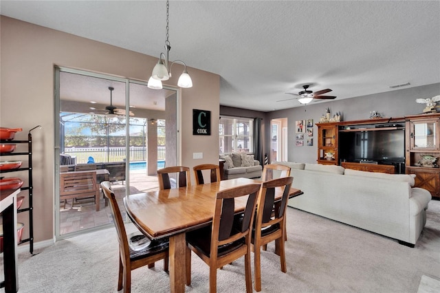 dining area featuring light carpet, a textured ceiling, and ceiling fan