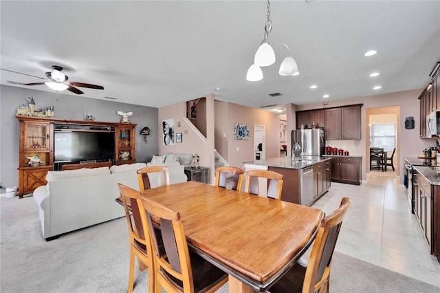 dining space with ceiling fan with notable chandelier, sink, and light carpet