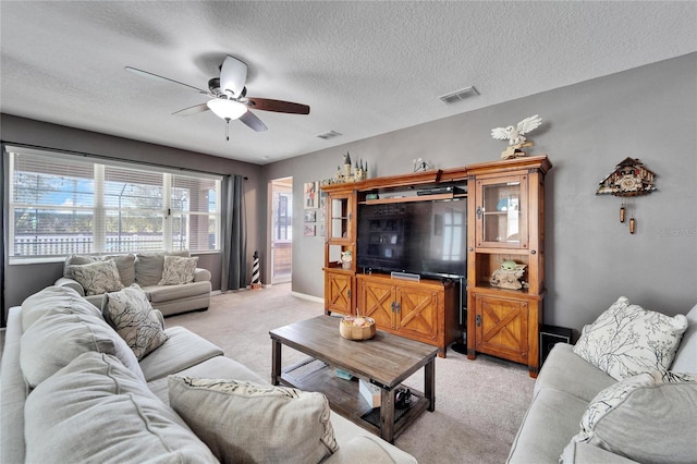 living room with ceiling fan, light colored carpet, and a textured ceiling