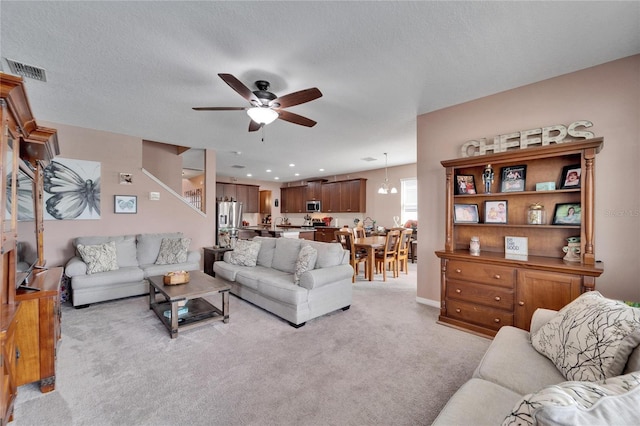 living room with light carpet, a textured ceiling, and ceiling fan