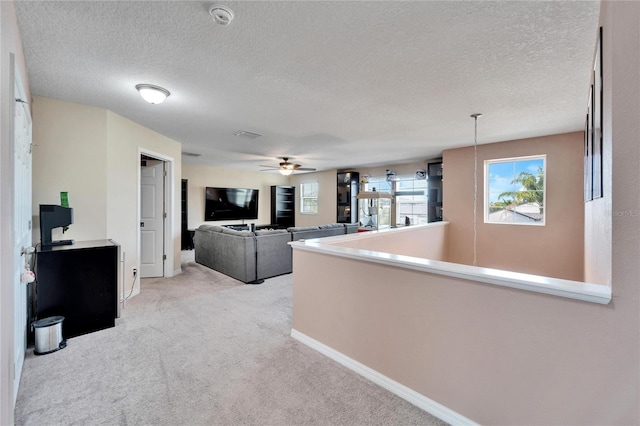 interior space featuring light carpet, a textured ceiling, and ceiling fan