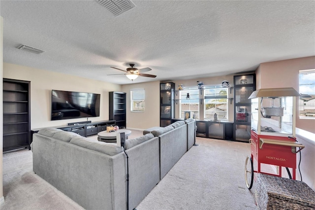 carpeted living room with ceiling fan, a healthy amount of sunlight, and a textured ceiling