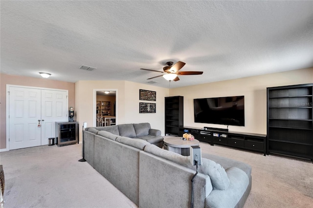 living room featuring a textured ceiling, ceiling fan, and light carpet