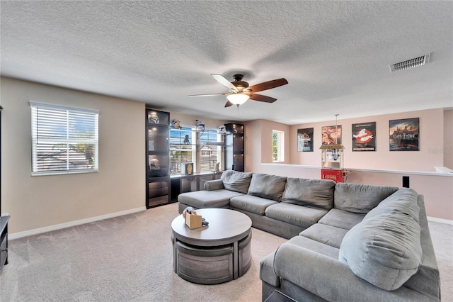 living room featuring carpet flooring, a textured ceiling, and ceiling fan