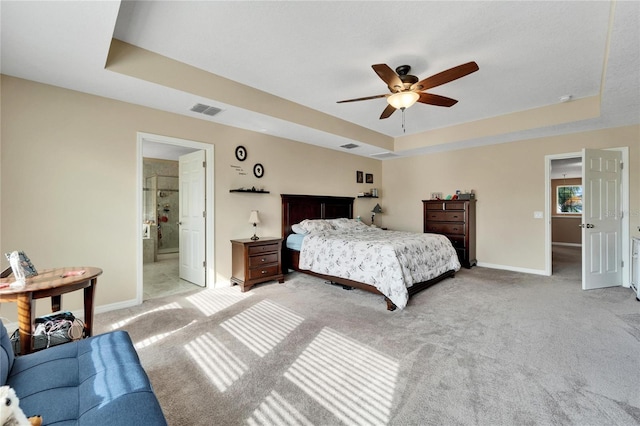 carpeted bedroom featuring connected bathroom, a raised ceiling, and ceiling fan