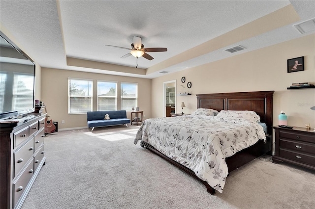 bedroom featuring a textured ceiling, a tray ceiling, ceiling fan, and light colored carpet