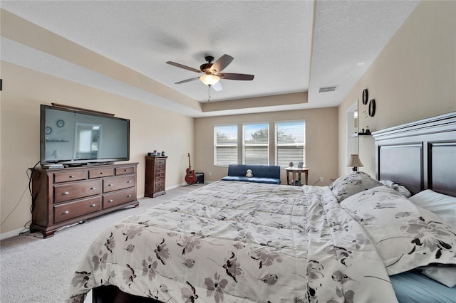 carpeted bedroom featuring a textured ceiling, a raised ceiling, and ceiling fan