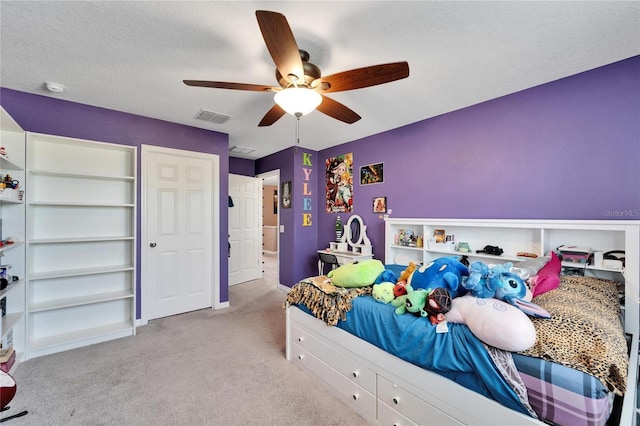 bedroom with a textured ceiling, light colored carpet, and ceiling fan