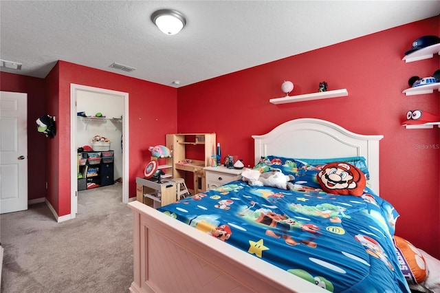 bedroom with a textured ceiling, a walk in closet, light colored carpet, and a closet